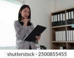 Manager. Conceptual Asian businesswoman wearing a suit working in a modern office. Take notes and create analytical plans on business files, careers, real estate project management, considerations.