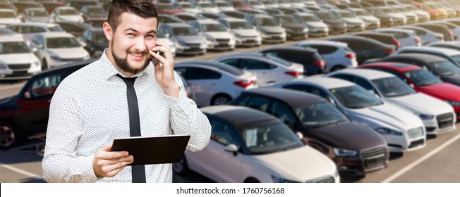 Manager with digital tablet and phone on a background of cars