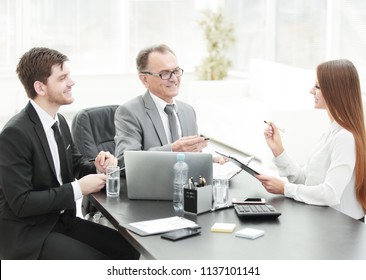 Manager discussing work issues with his assistants behind a Desk