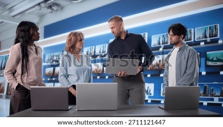 Manager Doing Laptop Comparison To Workers At Electronics Store, Showing Build Materials, Hinge Quality, And Keyboard.