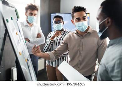 Manager employee in protective medical mask presenting new business strategy project to higher rank executive or director, making and showing graph diagram presentation on white board at office - Powered by Shutterstock