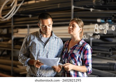 Manager and employee together checking availability of goods in the building materials warehouse