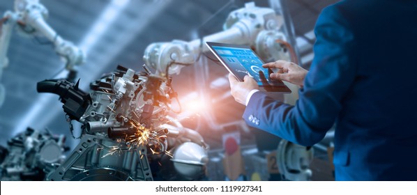 Manager engineer check and control automation robot arms machine in intelligent factory industrial on real time monitoring system software. Welding robotics and digital manufacturing operation.  - Shutterstock ID 1119927341