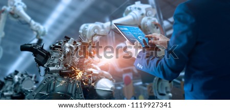 Manager engineer check and control automation robot arms machine in intelligent factory industrial on real time monitoring system software. Welding robotics and digital manufacturing operation. 