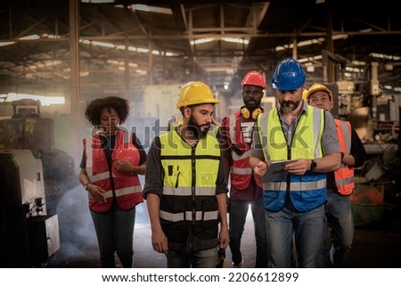 Manager Engineer holding tablet and talk with Technician, group of diversity teamwork, foreman and workers team in safety uniform, discussion while walking in heavy industry manufacturing factory.