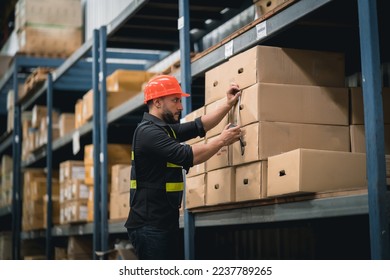 Manager or engineer man employee using tape measure for measuring dimension of product in cardboard box. Worker wearing high visibility clothing, helmet checking goods or boxes for delivery.