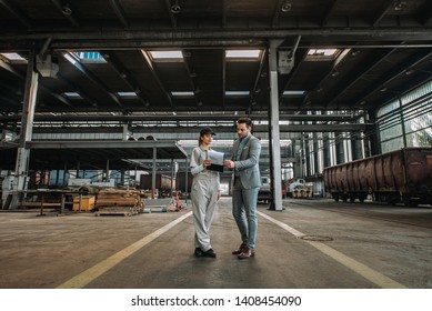 Manager and female worker talking at train factory hall. - Powered by Shutterstock