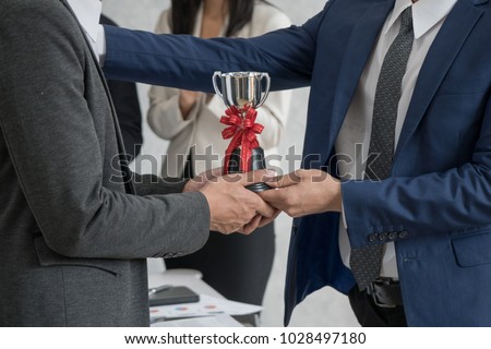 Manager giving employee the trophy award for success in business. 