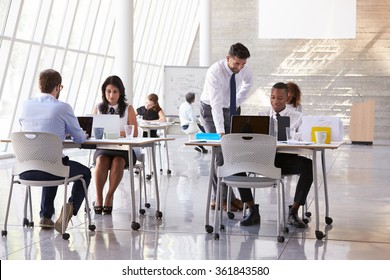 Manager Helping Staff In Busy Office Environment