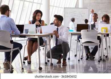 Manager Helping Staff In Busy Office Environment