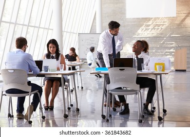 Manager Helping Staff In Busy Office Environment