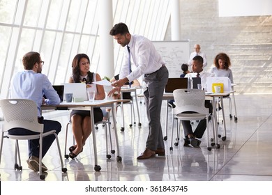 Manager Helping Staff In Busy Office Environment