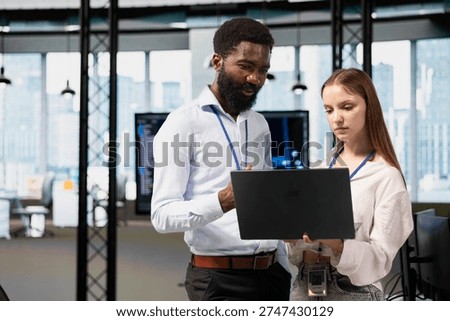 Manager helping young trainee coding during internship in tech startup using laptop. Team leader providing support to newcomer engineer using notebook in software development agency