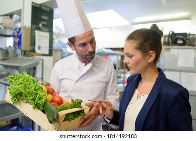 manager inspecting crate of vegetables chef is holding