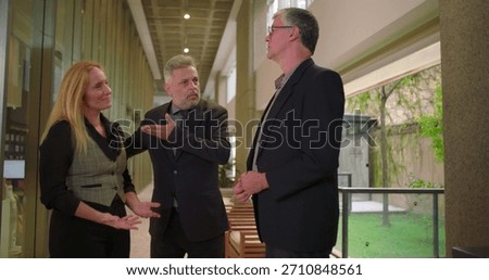 Manager introducing colleagues to one another in office hallway, professional team members exchanging greetings in corporate environment
