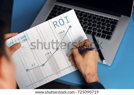 Manager makes a note on the graph of conversion sales and return on investment ROI. Internet marketing with the schedule up. Good indicators of contextual advertising.
