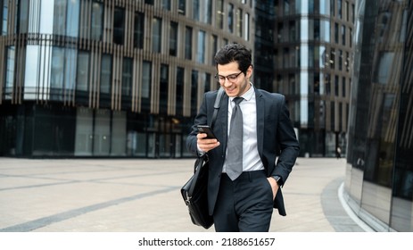 The manager is a man in a business suit going to work in the office, using an app on his phone - Shutterstock ID 2188651657