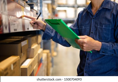 Manager Man Worker Doing Stocktaking Of Product Management In Cardboard Box On Shelves In Warehouse. Physical Inventory Count.
 Male Professional Assistant Checking Stock In Factory.