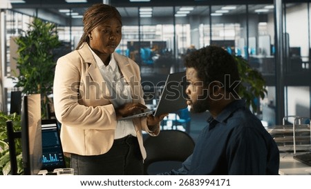 Manager in office ensuring worker hits key performance targets for revenue, profitability and operational efficiency. Corporate management executive board member talks with employee at work, camera A