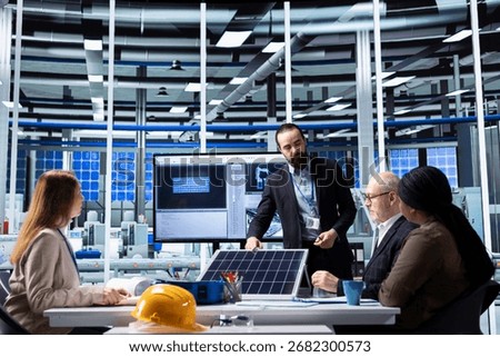 Manager presents solar panel technology and automated production concepts to factory executives in industrial facility, utilizing digital diagrams to illustrate investment and expansion strategy