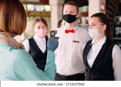 The Manager of a restaurant or hotel checks the body temperature of the staff with a thermal imaging device