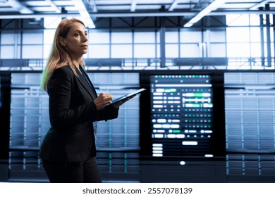 Manager in server room using tablet to implement and maintain security measures, protecting systems from unauthorized access. Woman in data center doing hardware maintenance with device