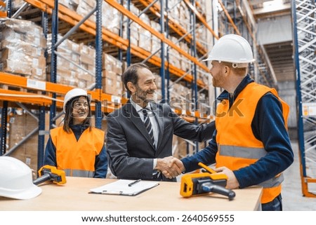 Manager shaking hands with a worker in a logistics warehouse, finalizing a successful business deal