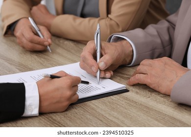 Manager showing client where he must to mark signature at light wooden table indoors, closeup - Shutterstock ID 2394510325