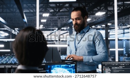 Manager supervising work of server room engineer using AI to review infrastructure diagnostics on devices. Tech company supervisor overseeing IT expert in data center analyzing data using AI, camera A