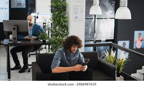 Manager taking notes on smartphone, trying to create new research project in company office. Businessman analyzing programming statistics to make decision, coworking space.