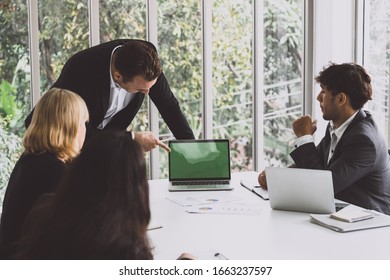 Manager talking with his Business Team in meeting room point his hand to laptop computer
