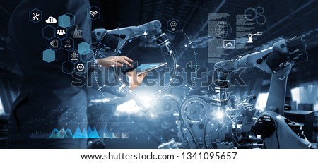 Manager Technical Industrial Engineer working and control robotics with monitoring system software and icon industry network connection on tablet. AI, Artificial Intelligence, Automation robot arm
