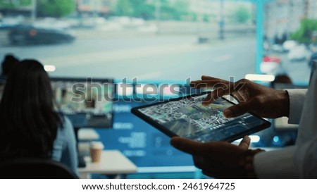 Manager tracking a delivery car by using satellite map for navigating around the city, monitoring orders via surveillance footage and CCTV system. Locating coordinates for shipping route. Camera B.