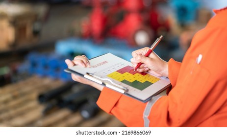 The manager is using ballpoint pen to marking on the risk assessment matrix at "High risk" level, with blurred background of factory place. Industrial and business working photo.