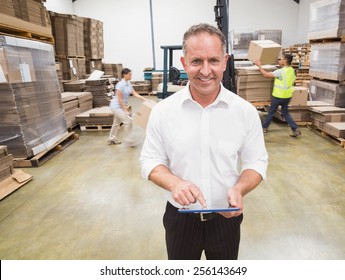 Manager using digital tablet during busy period in warehouse