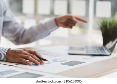 Manager Is Using A Laptop Computer While Analyzing The Company's Financial Statements On The Screen.