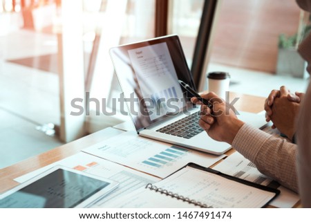 Manager is using a laptop computer while analyzing the company's financial statements on the screen.