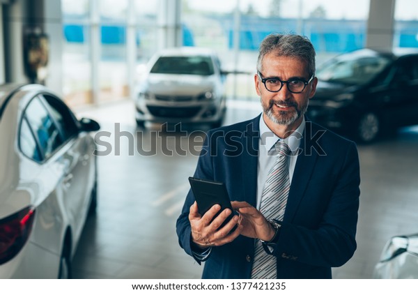 manager using tablet in car
showroom