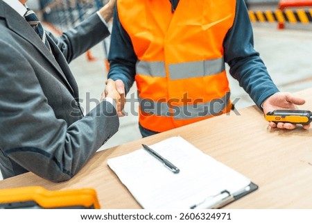 Manager and warehouse worker shaking hands after signing a contract in a logistics center