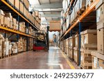 Manager wearing hard hat with digital tablet counts merchandise in warehouse. He walks through rows of storage racks with merchandise.	
