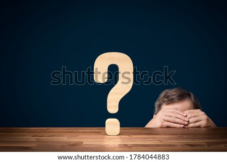 Manager is worried about future and decision making concept. Question mark symbolizing decision making and manager or businessperson hiding behind his hand and the table.