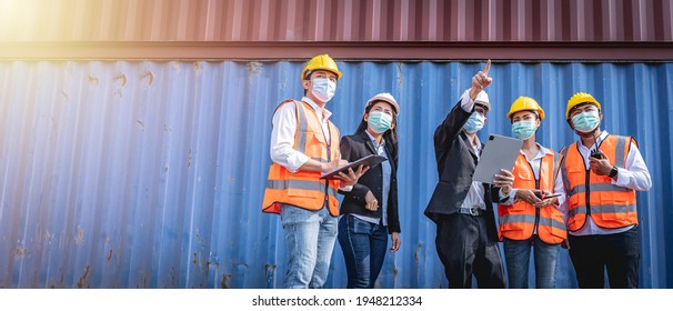 Managers and Engineers wearing face masks discussing work with shipping containers in the background. Coronavirus pandemic. Social distancing. - Powered by Shutterstock