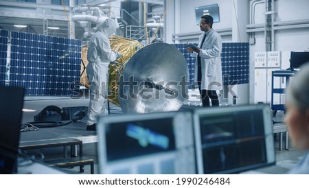 Managing Engineer and Chief Technician Working on Satellite Construction, Talk, Use Computer. Aerospace Agency Manufacturing Facility: Scientists Assemble Spacecraft for Space Exploration Mission