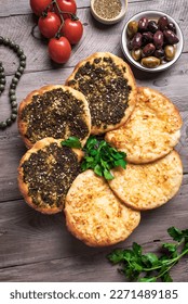 Manakeesh, arabic pizza, flat bread topped with zaatar spices and cheese. Homemade  mediterranean flat bread manakish on wooden table.