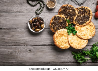 Manakeesh, arabic pizza, flat bread topped with zaatar spices and cheese. Homemade  mediterranean flat bread manakish on wooden table, copy space.