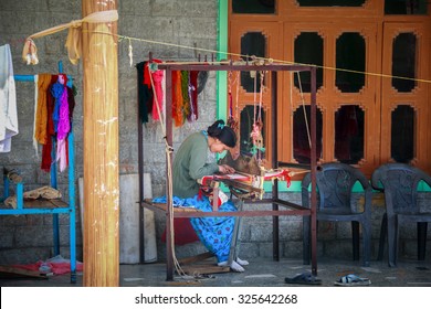 MANALI, HIMACHAL PRADESH, INDIA - 5 SEP: Woman weaves a colorful shawl on a traditional spinning machine on the veranda of the house in the Kullu Valley, Himachal Pradesh, India on 5 SEP 2015.