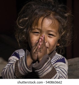MANANG VILLAGE, WESTERN NEPAL - OCTOBER 14, 2016 : Portrait young girl with folded hands in street . Close up