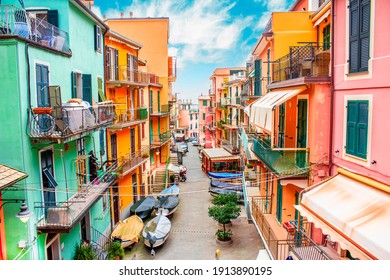 Manarola, Liguria Italy. Traditional typical Italian village in National park Cinque Terre, colorful multicolored buildings houses, fishing boats on road, blue cloudy sky