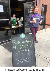 Manassas, Virginia / USA - April 4, 2020: A Customer Walks Away With Her Drink After Receiving It From A Smiling Starbucks Barista Set-up For Improvised Mobile Order Pickup During The COVID-19 Crisis.