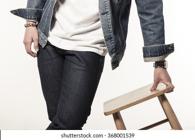 A Man(boy, Male, Model) Wearing Blue Denim(jeans) Jacket And Pants(trousers) Stand Up With The Wood Chair Isolated White At The Studio.